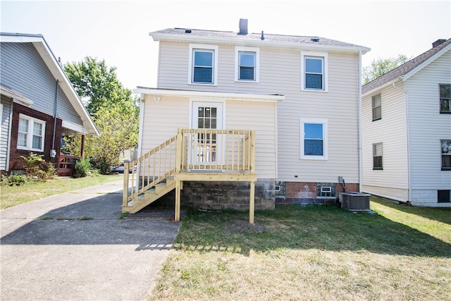 rear view of house featuring a lawn and central AC unit