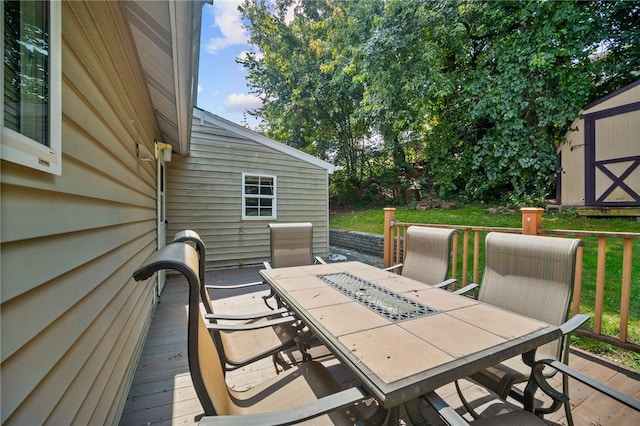 wooden deck with a storage shed, outdoor dining space, and an outbuilding