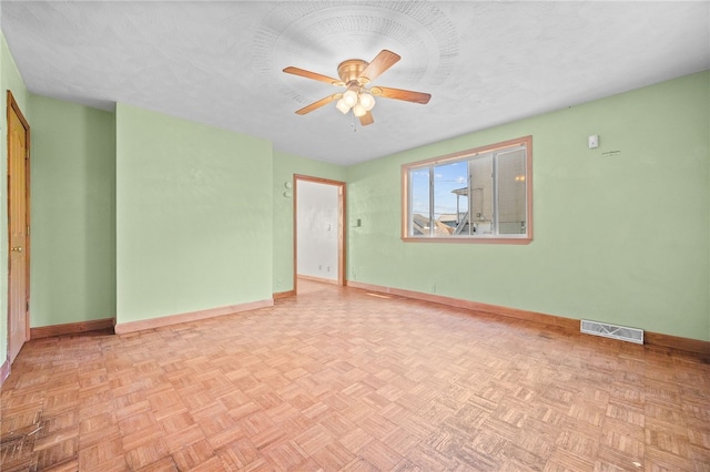 unfurnished room with light parquet flooring, ceiling fan, and a textured ceiling