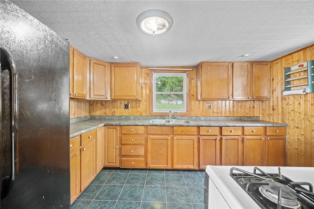 kitchen with wooden walls, a textured ceiling, white range oven, dark tile patterned floors, and sink