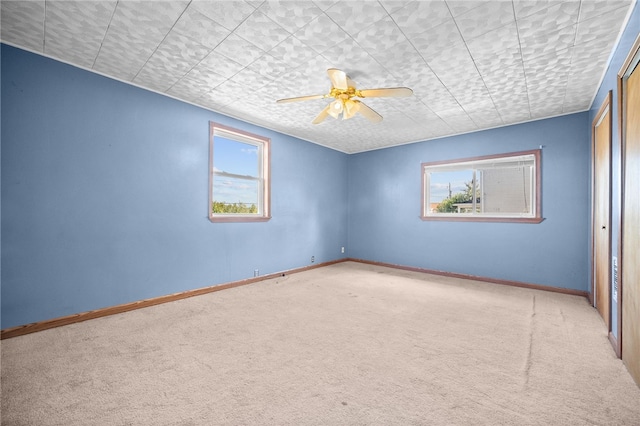 carpeted spare room featuring ceiling fan