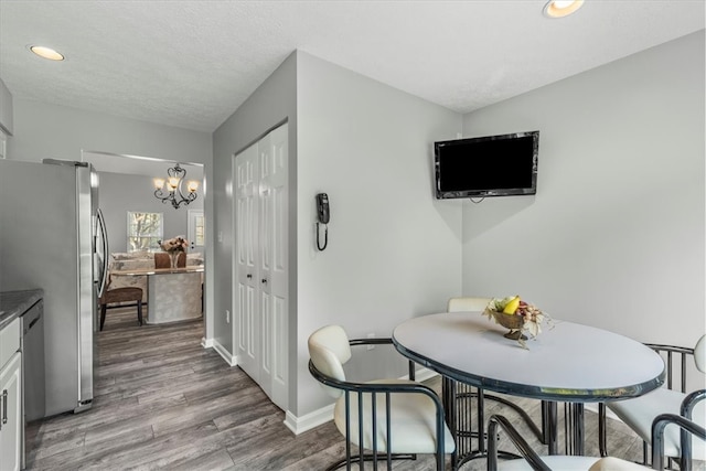 dining space with a chandelier, wood-type flooring, and a textured ceiling