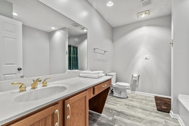 bathroom with hardwood / wood-style floors, vanity, toilet, and a textured ceiling