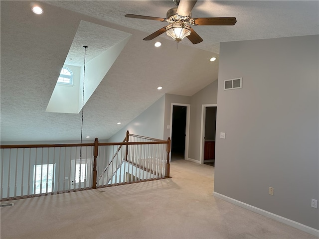 corridor featuring lofted ceiling, a textured ceiling, and light carpet