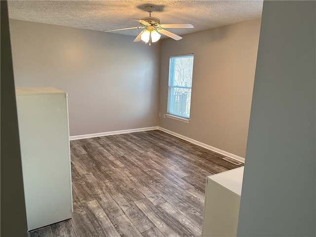 unfurnished room with ceiling fan, dark hardwood / wood-style flooring, and a textured ceiling