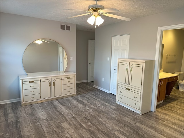 bedroom with ceiling fan, dark hardwood / wood-style flooring, a textured ceiling, and ensuite bath