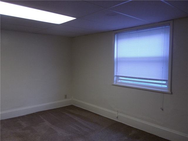 carpeted spare room featuring a drop ceiling