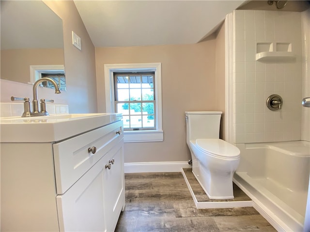 bathroom featuring vanity, hardwood / wood-style floors, tiled shower, and toilet