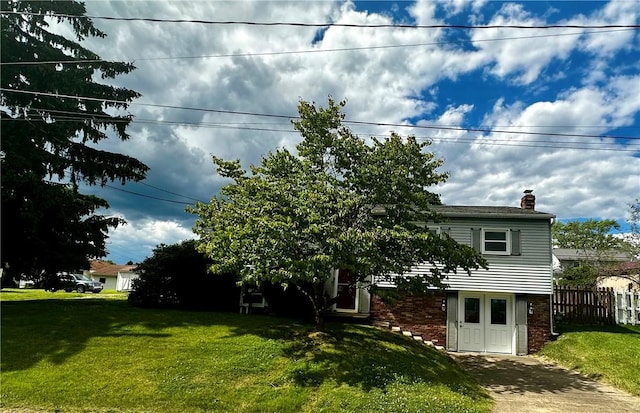 exterior space with a front lawn, a chimney, fence, and brick siding