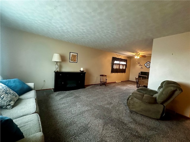 living room featuring ceiling fan, carpet flooring, and a textured ceiling