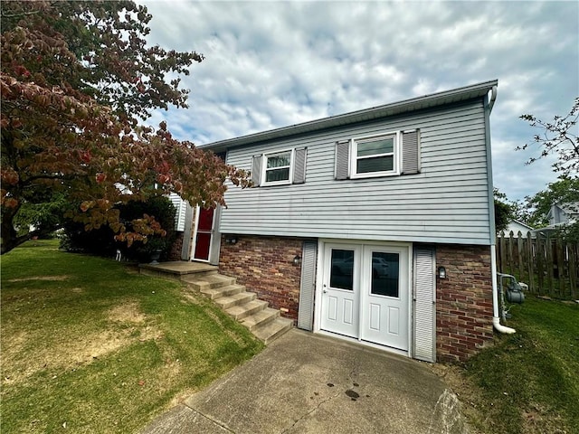 view of front facade featuring brick siding, a front yard, and fence