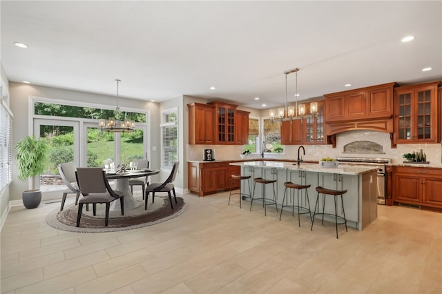 kitchen featuring a healthy amount of sunlight, high end range, an island with sink, and an inviting chandelier