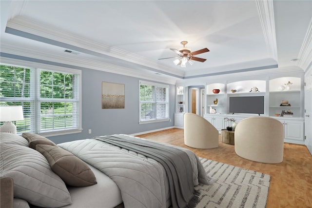 bedroom featuring light hardwood / wood-style floors, a raised ceiling, and crown molding