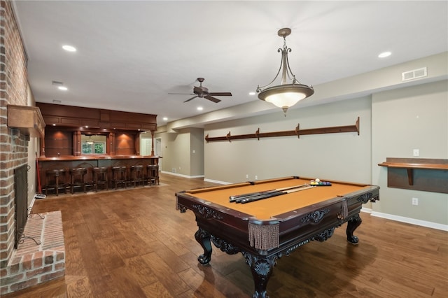 rec room with hardwood / wood-style floors, a brick fireplace, ceiling fan, bar, and pool table