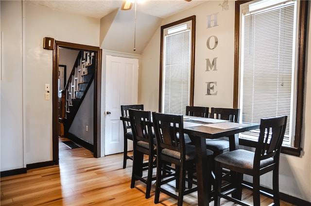 dining area featuring ceiling fan, vaulted ceiling, and light hardwood / wood-style flooring