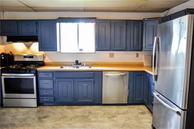 kitchen featuring blue cabinets, sink, extractor fan, appliances with stainless steel finishes, and a drop ceiling