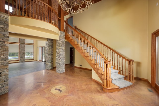 stairway featuring a towering ceiling, parquet floors, and a chandelier