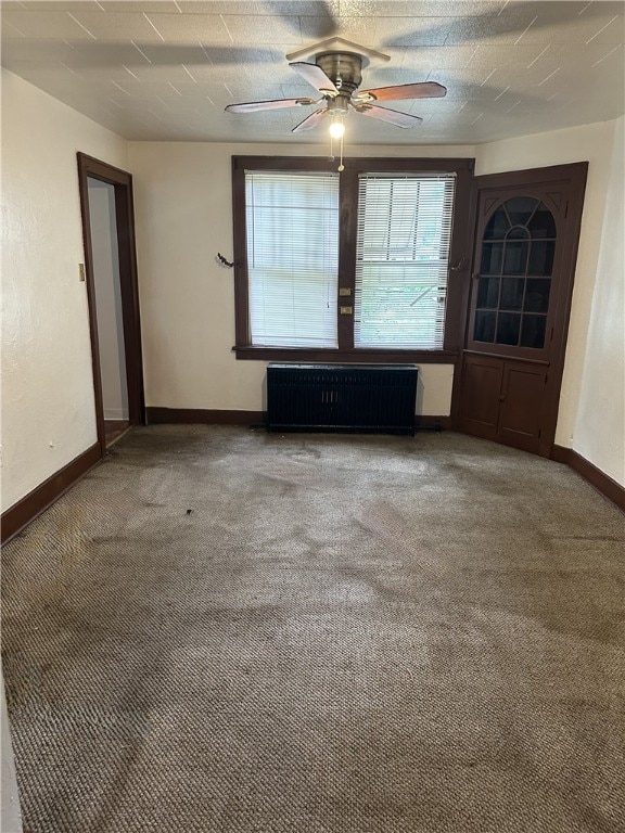 carpeted spare room featuring ceiling fan and radiator heating unit