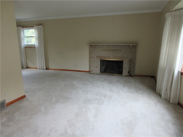 unfurnished living room with light colored carpet, ornamental molding, and a stone fireplace