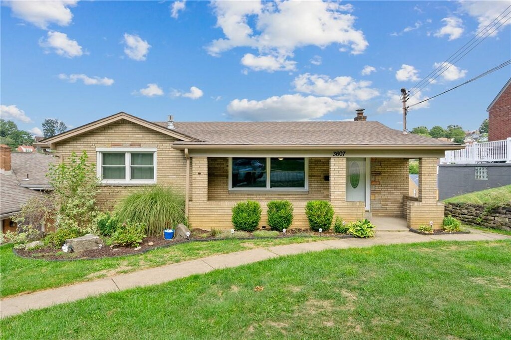 ranch-style house featuring brick siding, a front yard, and a shingled roof