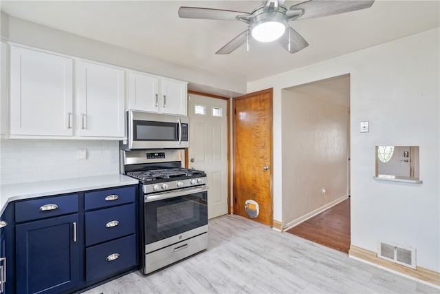 kitchen with appliances with stainless steel finishes, light hardwood / wood-style floors, tasteful backsplash, ceiling fan, and blue cabinets