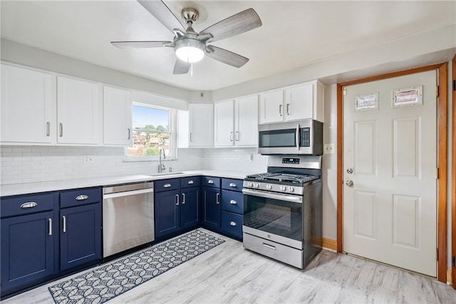 kitchen featuring ceiling fan, backsplash, blue cabinets, appliances with stainless steel finishes, and sink