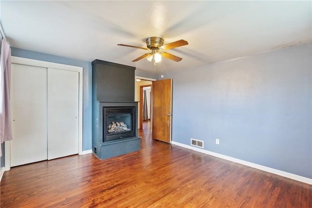 unfurnished living room with ceiling fan and dark wood-type flooring