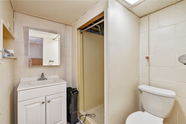 bathroom featuring toilet, vanity, and tile walls