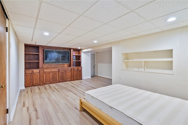 unfurnished bedroom with a paneled ceiling and light wood-type flooring