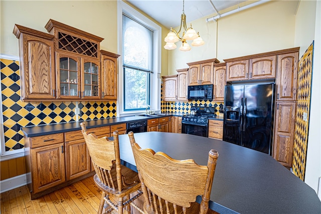 kitchen with light hardwood / wood-style flooring, backsplash, a chandelier, sink, and black appliances