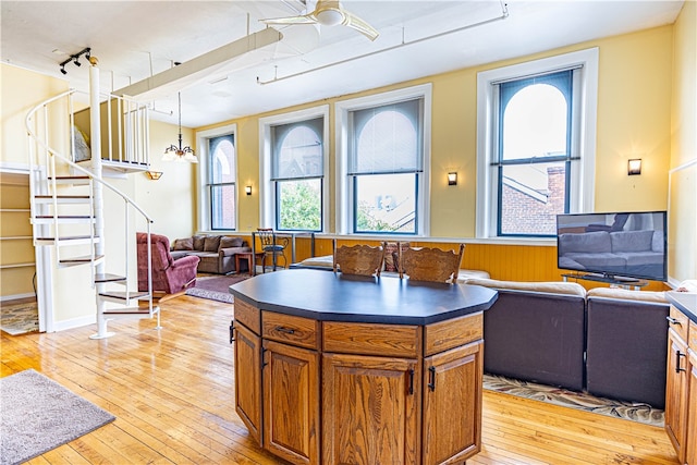 kitchen featuring ceiling fan, light hardwood / wood-style flooring, a kitchen island, and decorative light fixtures