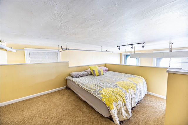 carpeted bedroom featuring track lighting