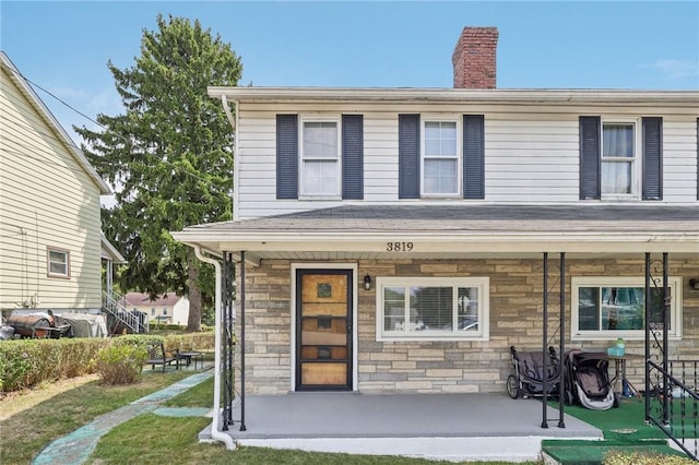 view of front of home featuring stone siding, a porch, and a chimney