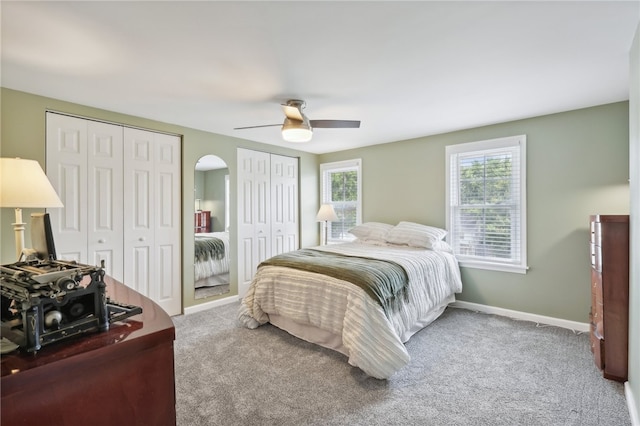 bedroom with ceiling fan, carpet flooring, and multiple closets