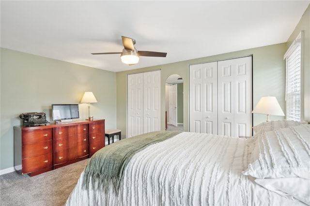 carpeted bedroom featuring ceiling fan and two closets