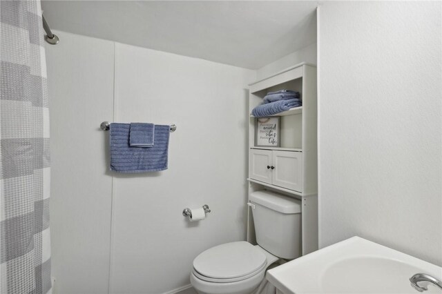 bathroom with curtained shower, vanity, and toilet