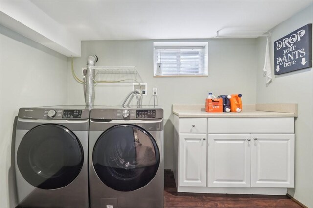 clothes washing area with washer and dryer, dark hardwood / wood-style floors, and cabinets