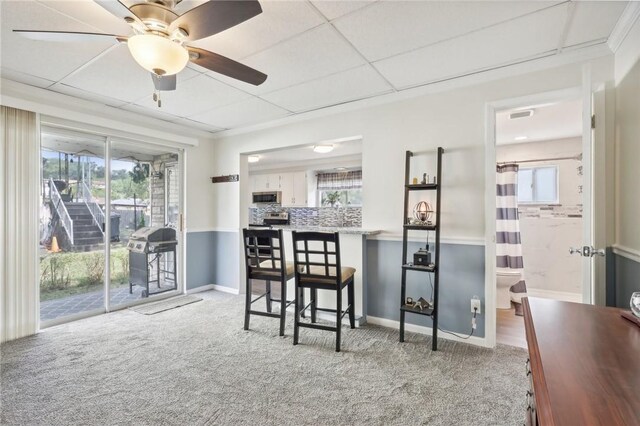 interior space with ceiling fan, light carpet, and a drop ceiling