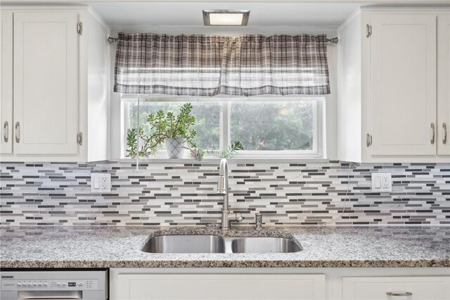 kitchen featuring sink, decorative backsplash, light stone countertops, washer / clothes dryer, and white cabinets