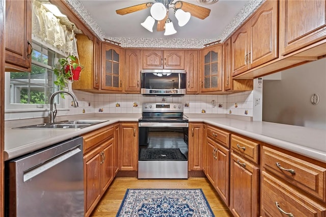 kitchen featuring stainless steel appliances, light hardwood / wood-style flooring, ceiling fan, and sink