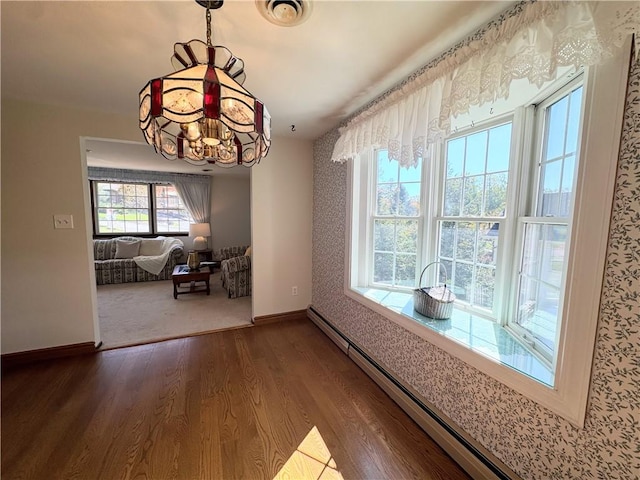 unfurnished dining area featuring wood-type flooring, a baseboard radiator, and a notable chandelier