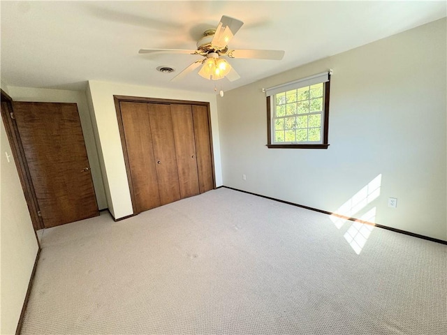 unfurnished bedroom with ceiling fan, light colored carpet, and a closet