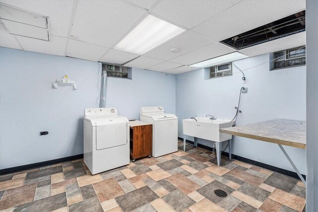 clothes washing area with sink, light tile patterned floors, and washing machine and clothes dryer