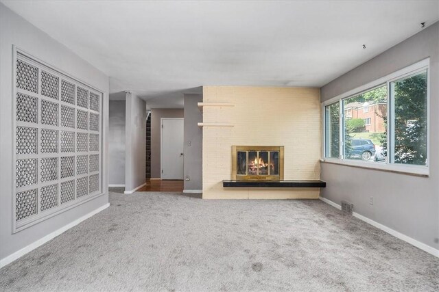 unfurnished living room with carpet and a fireplace