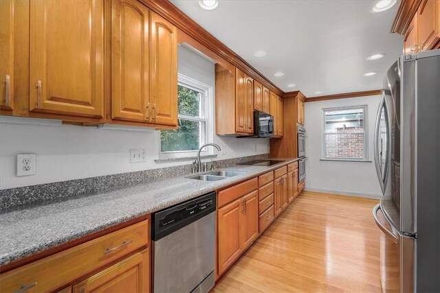 kitchen featuring ornamental molding, sink, black appliances, light wood-type flooring, and light stone countertops