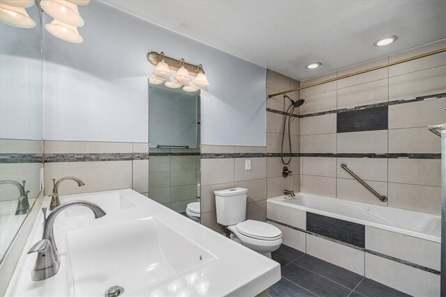 full bathroom featuring vanity, tile patterned flooring, tile walls, toilet, and tiled shower / bath combo