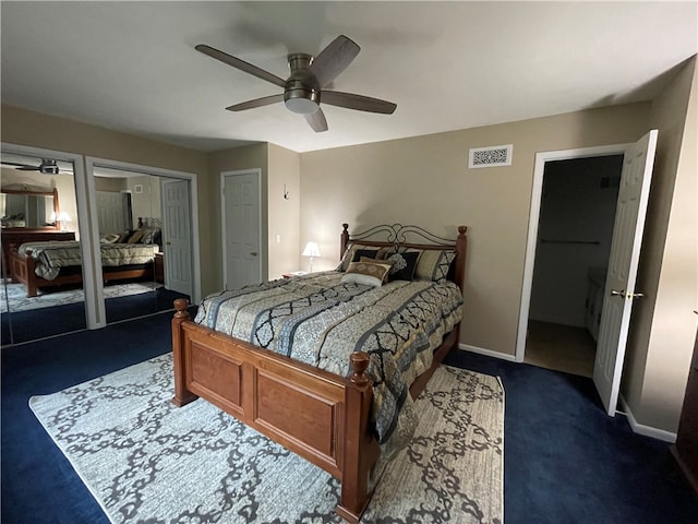 bedroom with multiple closets, ceiling fan, and dark carpet