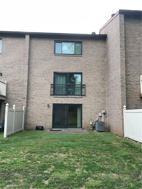 back of property featuring a yard, central AC, and a balcony