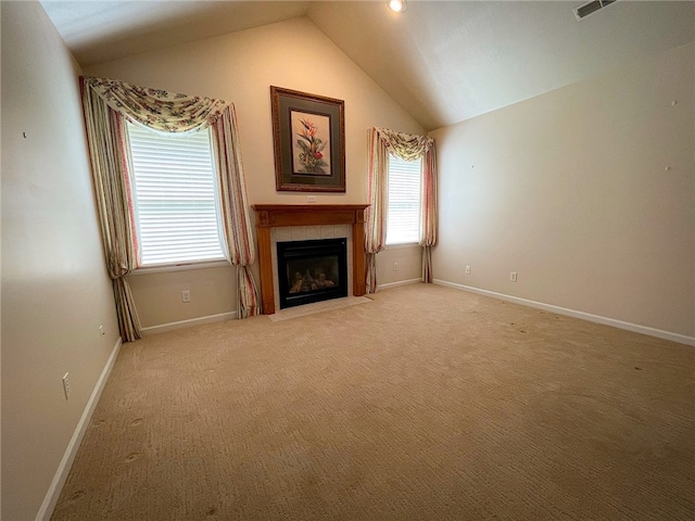 unfurnished living room featuring a tile fireplace, carpet, and vaulted ceiling