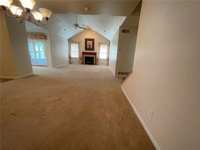 unfurnished living room featuring lofted ceiling, ceiling fan with notable chandelier, plenty of natural light, and carpet floors